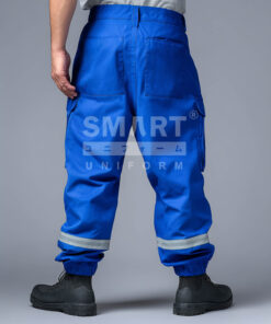 กางเกงยูนิฟอร์มทำงานขายาวสีน้ำเงินสด มุมด้านหลังเห็นช่วงเอวและตะเข็บกลางหลัง กระเป๋าหลังทรงเรียบ และกระเป๋าคาร์โก้ด้านข้างฝาปิด ช่วงปลายขามีจั๊มยางยืดพร้อมแถบสะท้อนแสงสีเงินคาดรอบขาทั้งสองข้าง ใส่รองเท้านิรภัยสีดำ ฉากสตูดิโอพื้นเทา