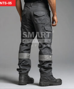 กางเกงยูนิฟอร์มทำงานขายาวสีเทาเข้ม มุมด้านหลังเห็นหูเข็มขัด กระเป๋าหลังทรงเรียบ และกระเป๋าคาร์โก้ด้านข้างฝาปิด ช่วงปลายขามีแถบสะท้อนแสงสีเงินคาดรอบขาทั้งสองข้าง ใส่รองเท้านิรภัย ฉากสตูดิโอพื้นเทา