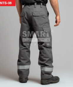 กางเกงยูนิฟอร์มทำงานขายาวสีเทาเข้ม มุมด้านหลังเห็นหูเข็มขัด กระเป๋าหลังฝาปิดทรงเรียบ และกระเป๋าคาร์โก้ด้านข้างฝาปิด ช่วงปลายขามีแถบสะท้อนแสงสีเทาเงินคาดรอบขาทั้งสองข้าง ใส่รองเท้านิรภัยสีดำ ฉากสตูดิโอพื้นเทาอ่อน