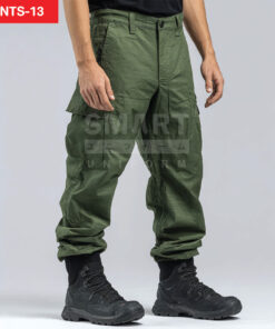 กางเกงยูนิฟอร์มทำงานขายาวสีเขียวโอลีฟ ทรงกระบอกเอวปกติ มีกระดุมและซิปหน้า พร้อมหูเข็มขัด กระเป๋าข้าง และกระเป๋าคาร์โก้ต้นขาฝาปิดทั้งสองข้าง ปลายขาเป็นจั๊มยางยืด ใส่รองเท้าบูททำงานสีดำ ฉากสตูดิโอพื้นขาวเทา