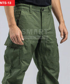 รายละเอียดกางเกงยูนิฟอร์มทำงานสีเขียวโอลีฟ เห็นขอบเอวพร้อมหูเข็มขัด กระดุมและซิปหน้า ตะเข็บเสริมแน่น และกระเป๋าคาร์โก้ฝาปิดที่ต้นขาด้านข้าง ถ่ายสตูดิโอพื้นขาวเทา