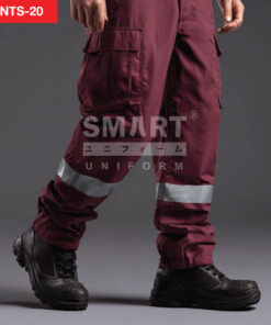 รายละเอียดกางเกงยูนิฟอร์มทำงานสีแดงไวน์เข้ม เห็นกระเป๋าคาร์โก้ฝาปิดที่ต้นขา ตะเข็บเดินเสริมความทน และแถบสะท้อนแสงสีเงินคาดรอบช่วงน่อง ปลายขาจั๊มยาง ใส่รองเท้านิรภัยสีดำ ถ่ายสตูดิโอพื้นเทาเข้ม