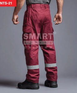 กางเกงยูนิฟอร์มทำงานขายาวสีแดงเลือดหมู มุมด้านหลังเห็นหูเข็มขัด แนวตะเข็บช่วงสะโพก และกระเป๋าคาร์โก้ด้านข้างฝาปิดทั้งสองข้าง ช่วงปลายขามีแถบสะท้อนแสงสีเงินคาดรอบขาทั้งสองข้าง ใส่รองเท้านิรภัยสีดำ ฉากสตูดิโอพื้นเทาเข้ม