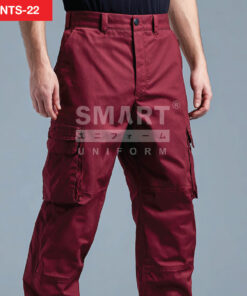 รายละเอียดกางเกงยูนิฟอร์มทำงานสีแดงไวน์ เห็นกระเป๋าคาร์โก้ฝาปิดที่ต้นขา แนวตะเข็บเสริมความทน และรอยต่อผ้าช่วงเข่าชัดเจน ใส่รองเท้านิรภัยสีดำ ถ่ายสตูดิโอพื้นเทาอ่อน